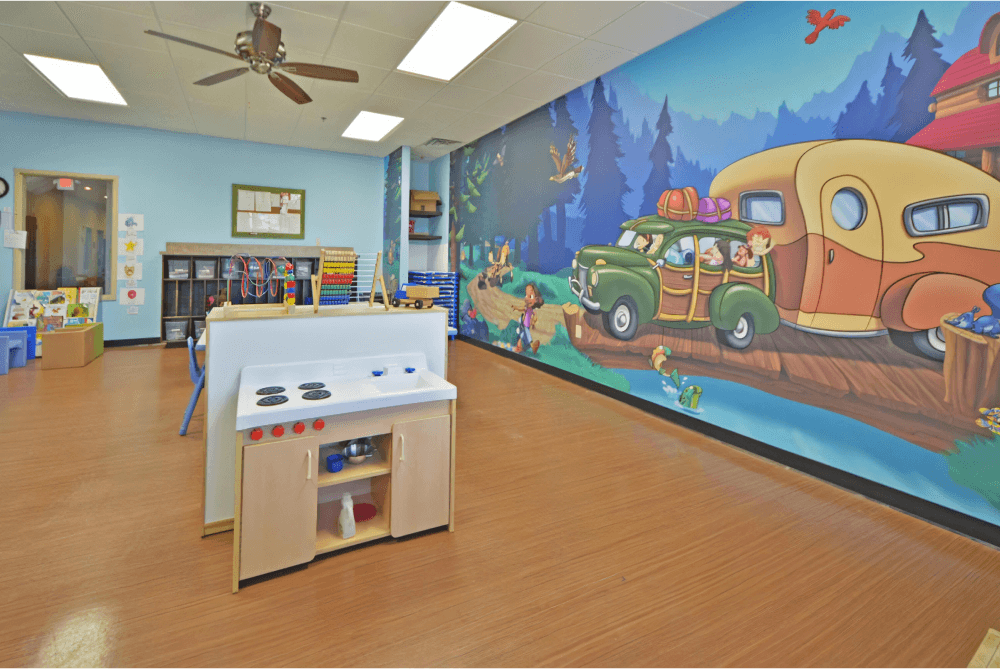 Childcare room with a camping mural, and toys throughout the room.
