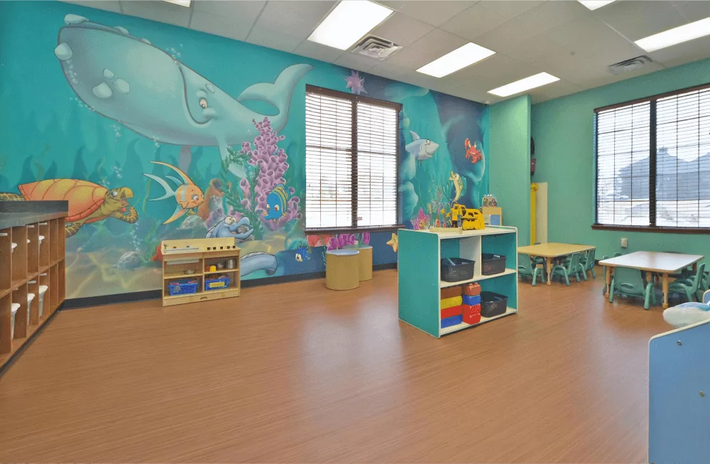 Toddler room with blue ocean mural and storage containers filled with toys