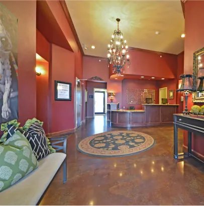 Lobby with red walls, brown stone floors, and a chandelier hanging from the ceiling.
