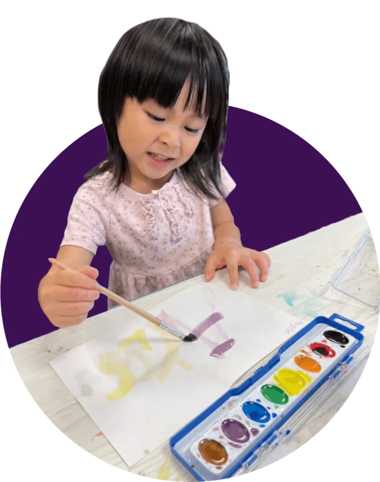 Young girl using watercolor paints on a sheet of paper.