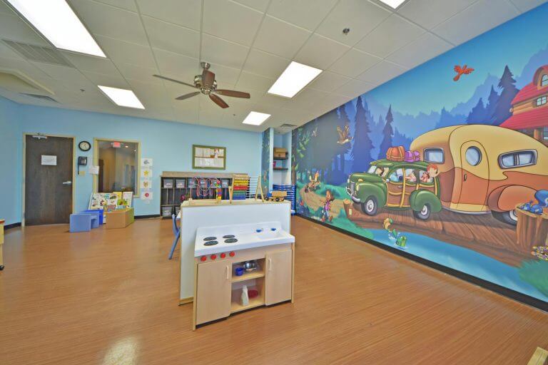 childcare classroom with a camper mural and toys in the center