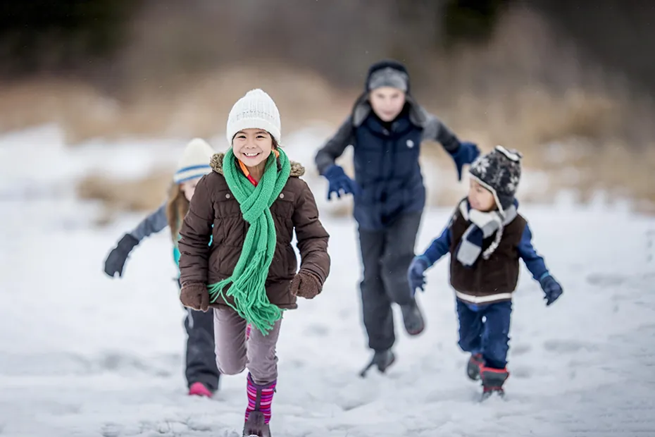 Kids running in the snow laughing.